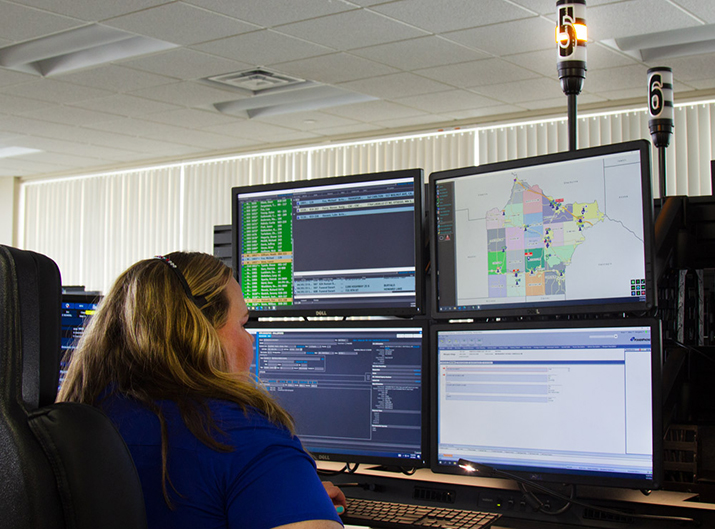 A 911 dispatcher sits in front of several computer screens.