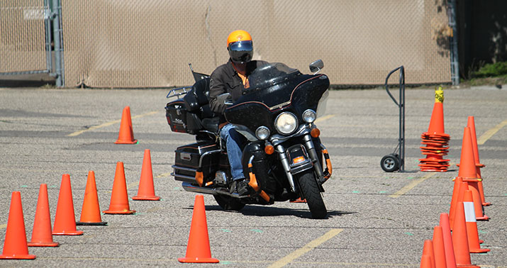Photo of a motorcycle rider driving through a series of cones.