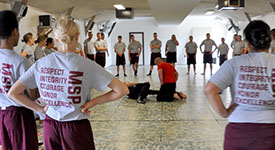 State Patrol cadets standing in a circle around an instructor and a cadet during a self-defense class