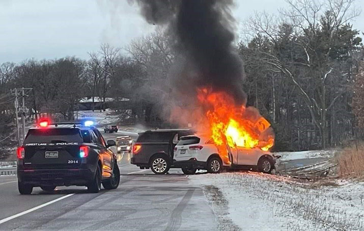 The crash scene showing Angie Kupczak’s vehicle on fire and the other driver's vehicle against the driver's side. A police vehicle with flashing lights