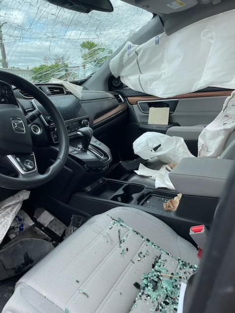 The interior of a vehicle with broken glass and deployed air bags.