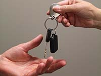 Two hands with car keys being handed over