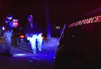 A motorist performs a field sobriety test during a traffic stop as an officer watches