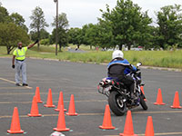 A motorcycle rider going through a training course as a rider coach watches
