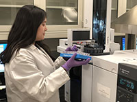 A lab technician carrying a tray of samples to a machine