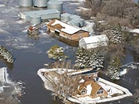 A home and farm buildings surrounded by floodwaters