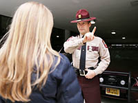 A woman performs a field sobriety test for a state trooper