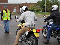 Two motorcyclists listen to an instructor at a training course