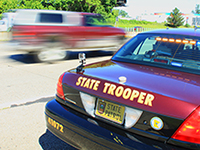 A vehicle driving by a stopped squad car