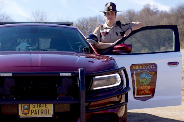 A state trooper standing by a squad car