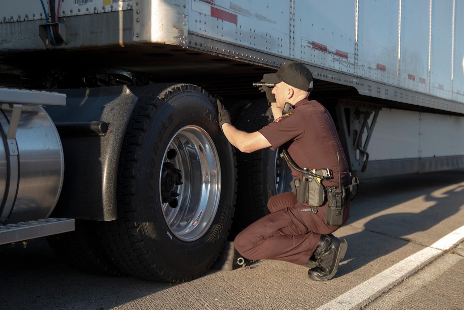 Commercial vehicle inspector looking under semi