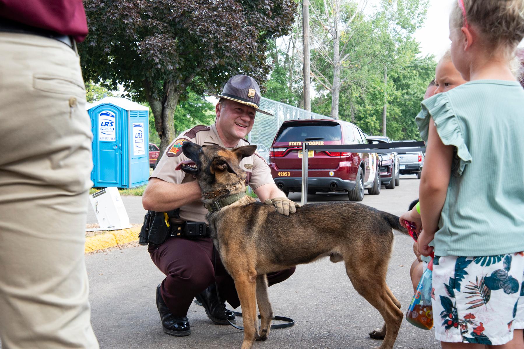 Trooper kneeling down petting K-9