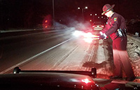 A trooper lights a flare for a stalled car.