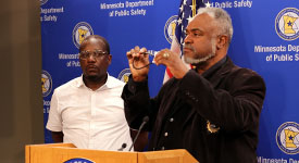 DPS Commissioner John Harrington holds up a gun lock during a news conference.