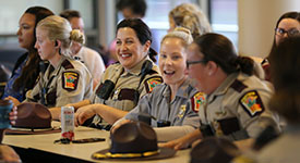 Female troopers, capitol security officers and support staff at a table during a meeting
