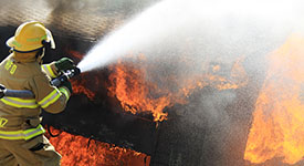 A firefighter spraying water on flames