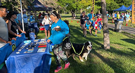 A woman with a dog visits the Office of Pipeline Safety booth at the 811 5K Run/Walk.