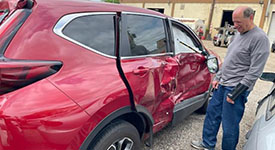 A man standing next to a damaged car