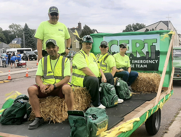 A group of volunteers with a local Community Emergency Response Team rides on a parade float.