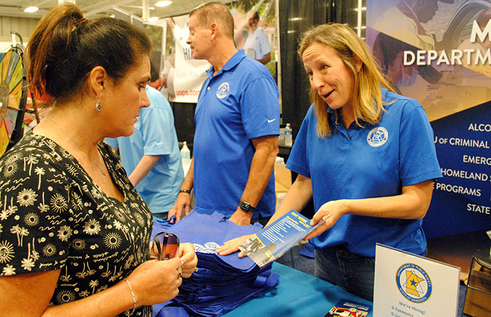 A DPS staff member talks with a woman visiting a DPS booth at an event
