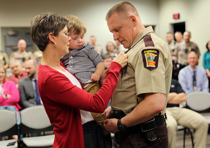 Woman pins new badge on trooper