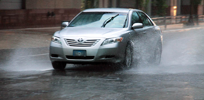 A car driving in the rain without headlights on