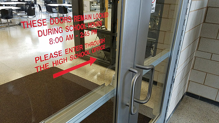 Locked school doors with directions to enter through the office