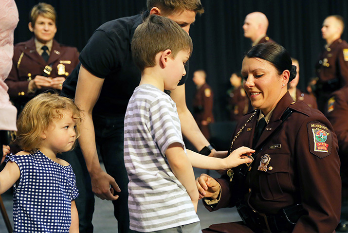 A child pins a badge on a new state patrol trooper at graduation
