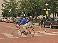 Two bicyclists and a pedestrian crossing a street at a crosswalk
