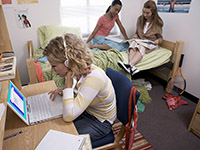 Three students studying in a dorm room.