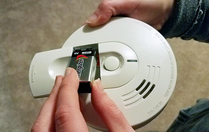 A battery being inserted into a smoke alarm
