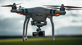 An unmanned aerial vehicle with a camera hovering over a green field