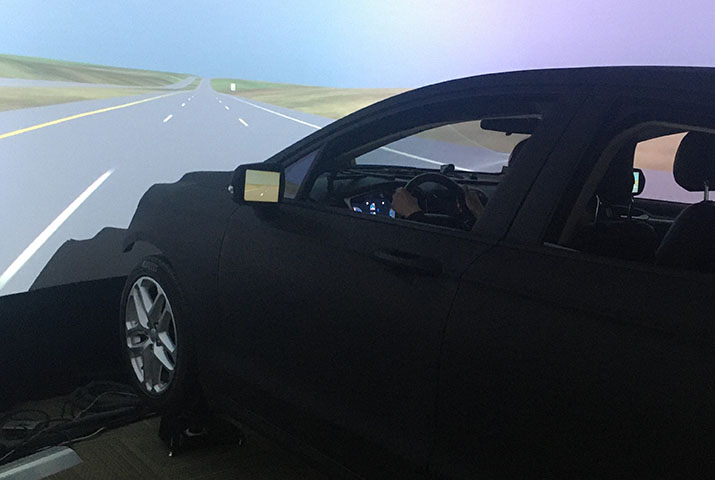 A driving simulator with a car appearing to drive along a road
