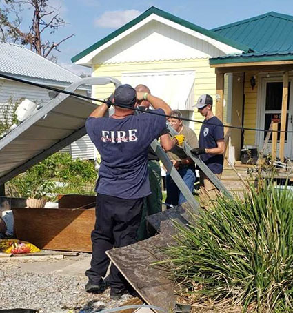 Minnesota firefighters check on a resident amid hurricane debris outside a home