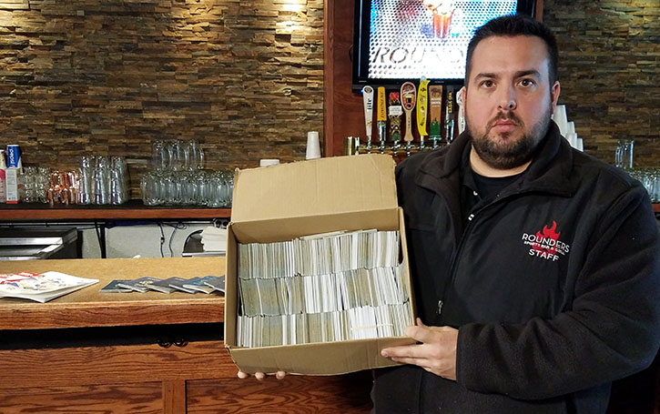 Ryan Tucker of Rounders Sports Bar and Grill in Mankato shows the staggering amount of fake IDs collected by his staff in 2016.