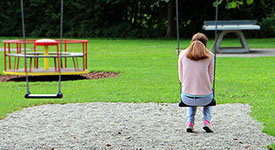 A young woman sitting on a swing at a playground