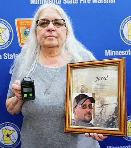 Denice Johnson holds a picture of her son Jared and a carbon monoxide detector.