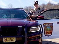 A state trooper standing by a squad car