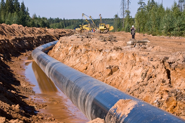 oil pipeline in ground with safety inspector in background