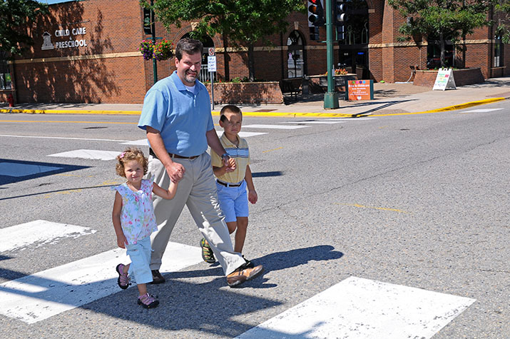 A man and two children using a crosswalk to cross a street