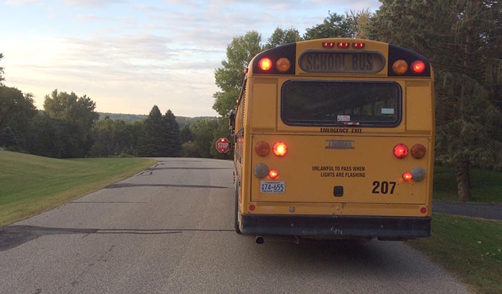 A school bus with red lights flashing and the stop arm extended