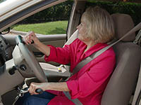 An older woman in the driver's seat of a vehicle