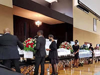 Five caskets at the front of a church during a visitation
