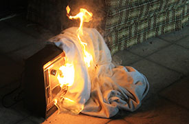 A blanket catching fire after it was thrown over a space heater.