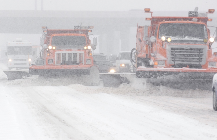 Multiple snow plows on a busy highway
