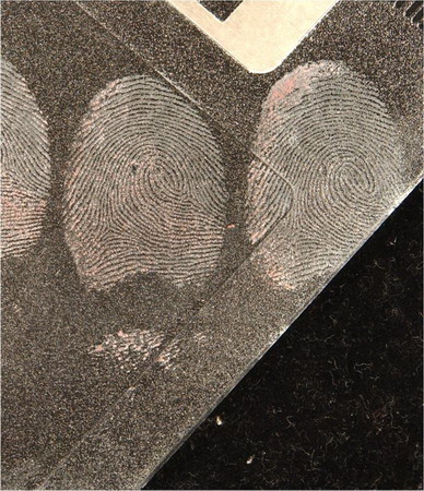 fingerprints in blood on a black floppy disc and the results of enhancement using Titanium Dioxide