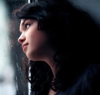 Sad young woman looking out window