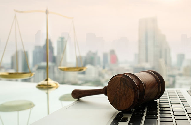 Justice scales, gavel and laptop with skyline background