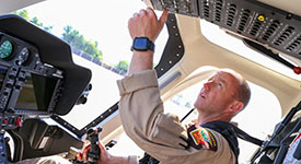 A state patrol pilot reaches for a switch inside the cockpit of a helicopter