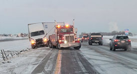 A tow truck removing a crashed semi truck after a winter crash.